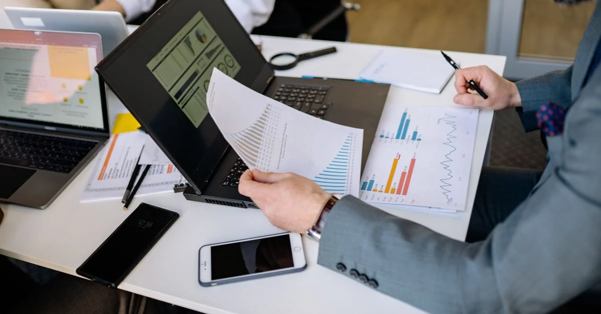 Des professionnels analysant des graphiques sur des ordinateurs portables lors d'une réunion d'affaires.