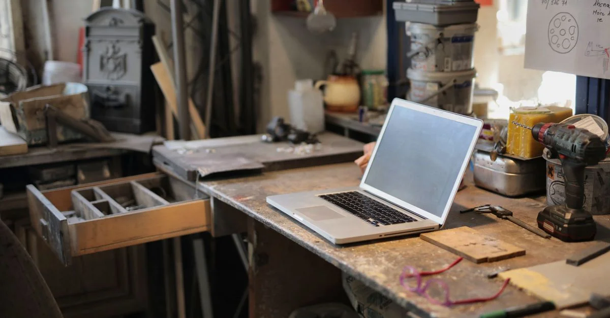 Un espace de travail organisé avec un ordinateur portable et divers outils dans un cadre d'atelier.