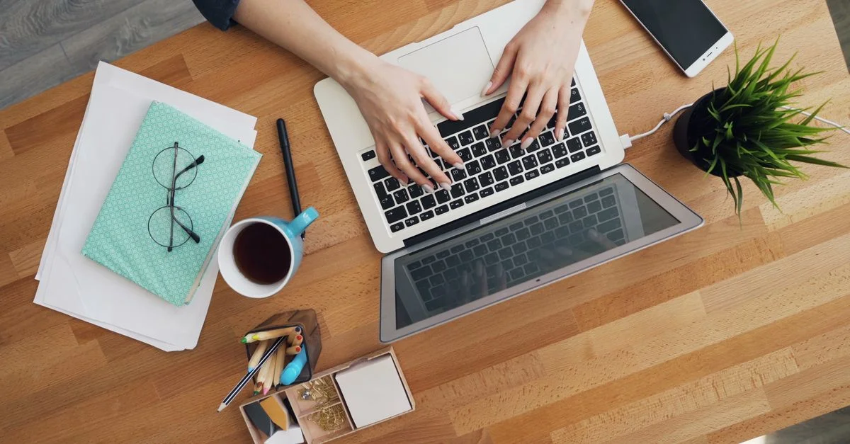 Vue aérienne d'un bureau contemporain avec un ordinateur portable, du café et des accessoires, mettant l'accent sur la productivité.