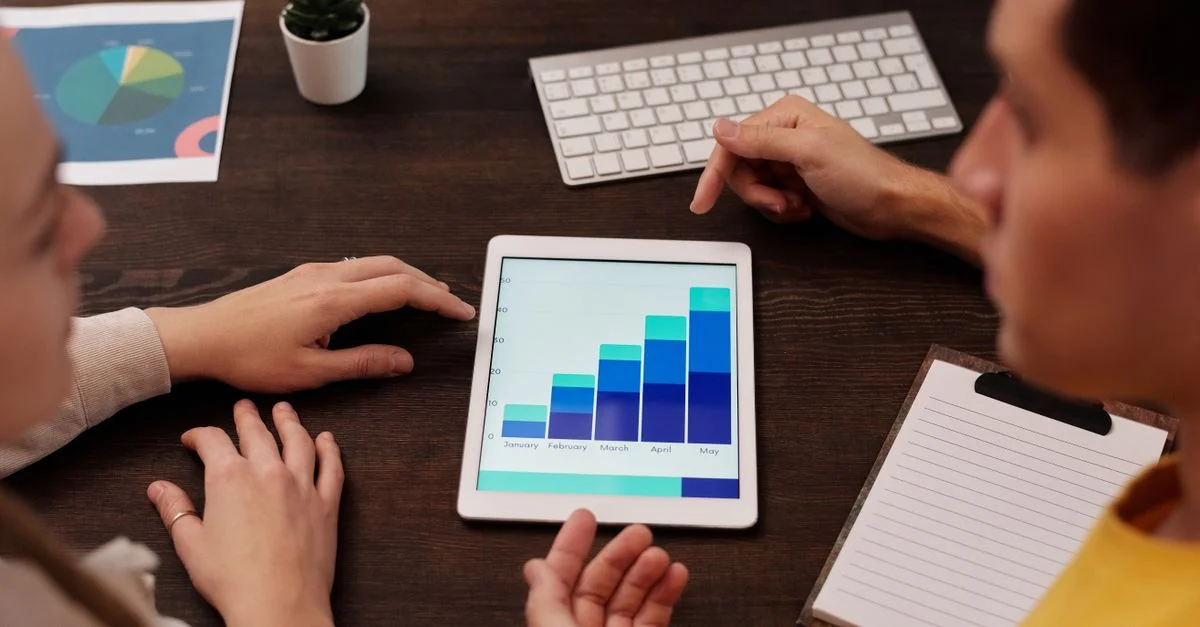 Des membres de l'équipe discutent de graphiques numériques sur une tablette dans un environnement de bureau moderne.