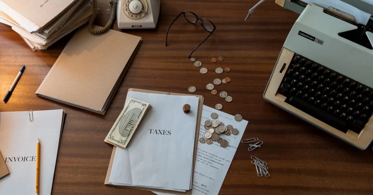 Espace de travail vintage avec une machine à écrire, des documents et un téléphone sur un bureau en bois, évoquant un cadre de bureau classique.